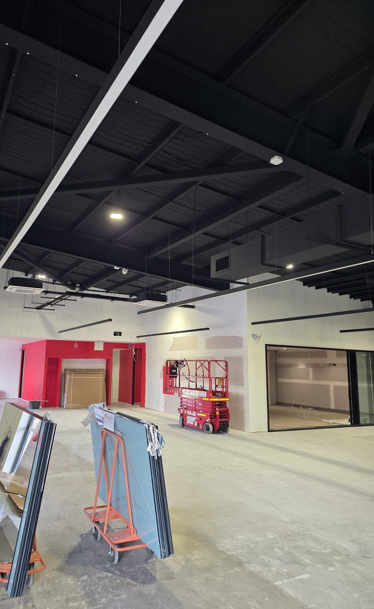 In progress: suspended linear lights being installed under a black ceiling