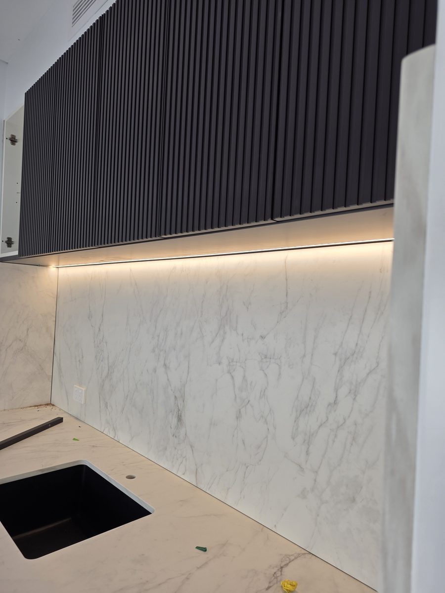 Fit-off: under-cabinet LED washing a marble splashback above an undermount sink, Picnic Point duplex